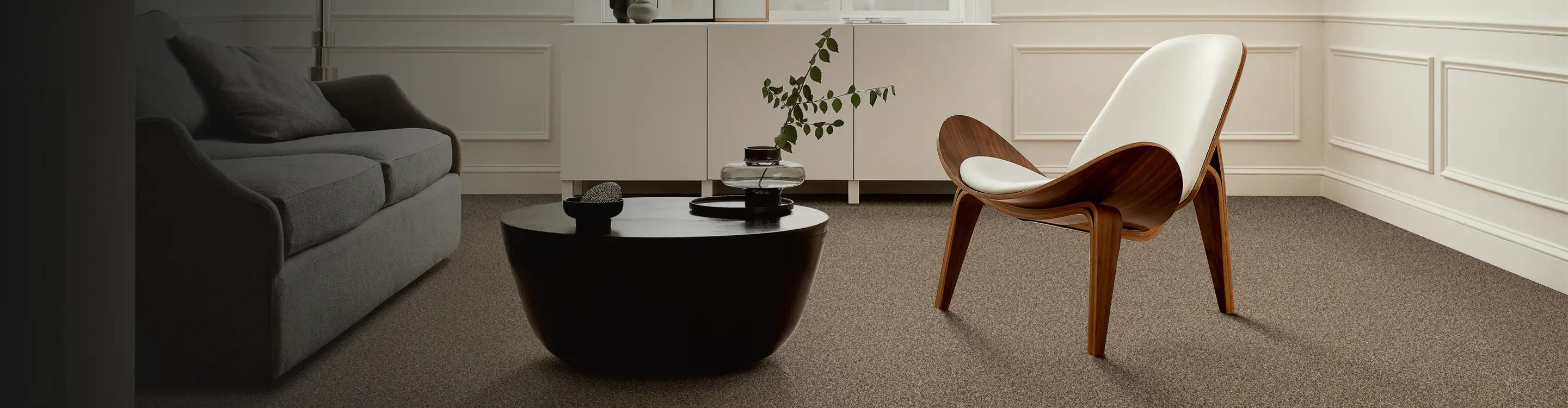 plush neutral carpet in contemporary living room with black coffee table, modern white chair and abstract art